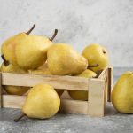 Bunch of fresh bio pears in wooden box on marble surface. High quality photo